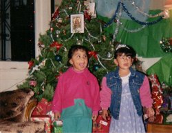 Two young girls standing in front of a Christmas tree and presents