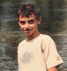 Boy wearing white t-shirt standing in front of a stream