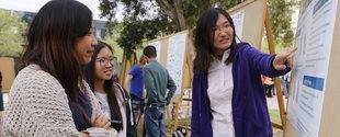Student presenting research poster to other students