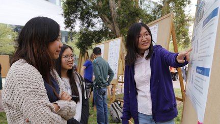 Student presenting research poster to other students