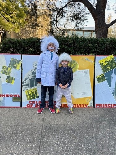 2 children, wearing Einstein wigs and mustaches stand in front of display posters, near Beckman Auditorium, prior to the Watson Lecture