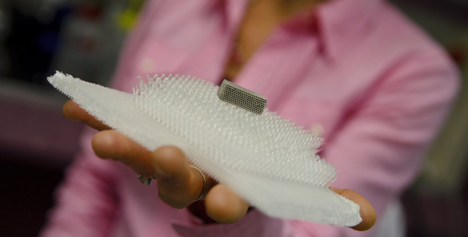 Julia Greer holds microtruss structure in the palm of her hand.