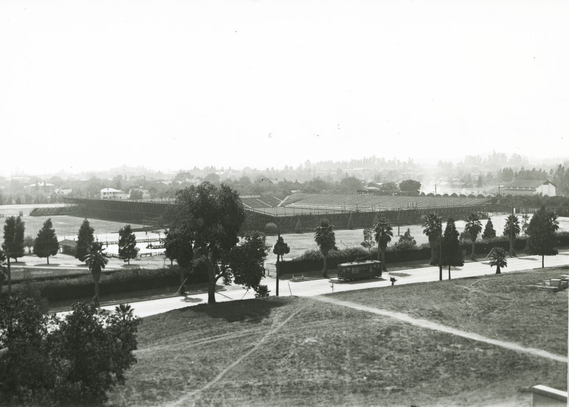A 1910, black-and-white photograph of Tournament Park in which a streetcar travels a street in front of a stadium.