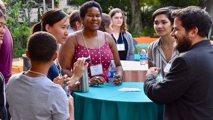 Students gather around tables at an event