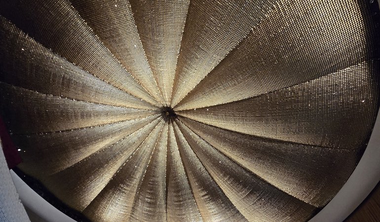 Ceiling view of inside Beckman Auditorium, dome-shaped chandelier made of golden lights radiating from the center.