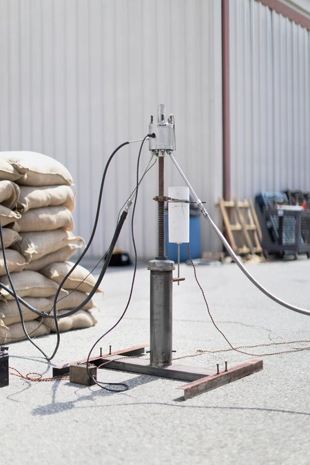 A stand composed of hardware recreates a very simple 1930s-era rocket launcher, from which numerous cables snake out.