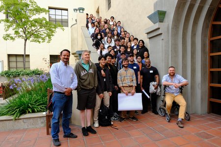 Mentors, mentees, and organizers arranged along a set of stairs outside. One man is sitting in a wheel chair in the lower right corner.