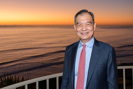 Cropped photo of man in suit standing in front of a sunset