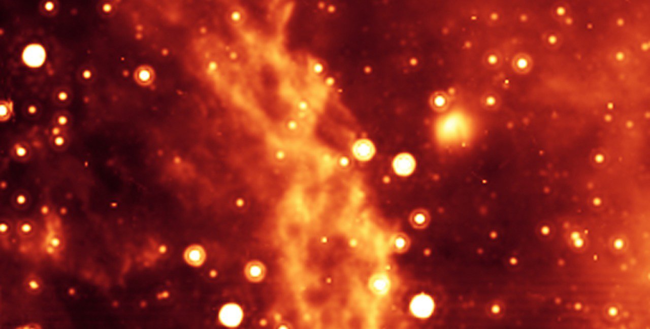 Astronomical image of the Double Helix Nebula in the Milky Way Galaxy. The nebula appears as two twisting ropes in orange surrounded by stars appearing as orange spots.