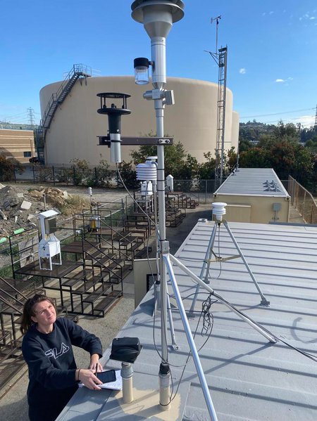 A female graduate student works with one of the aerosol measuring instruments on the roof of the ASCENT site, which is housed in a shipping container.