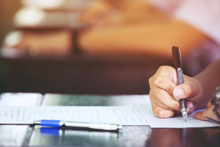 Stock photo of a person's hand writing on a paper at a desk