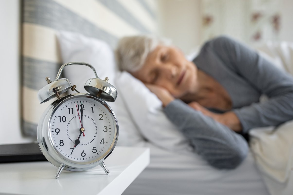 Stock image of a person sleeping next to an alarm clock