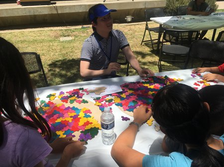 People sit at a table, tiling together brightly colored pieces of a single shape