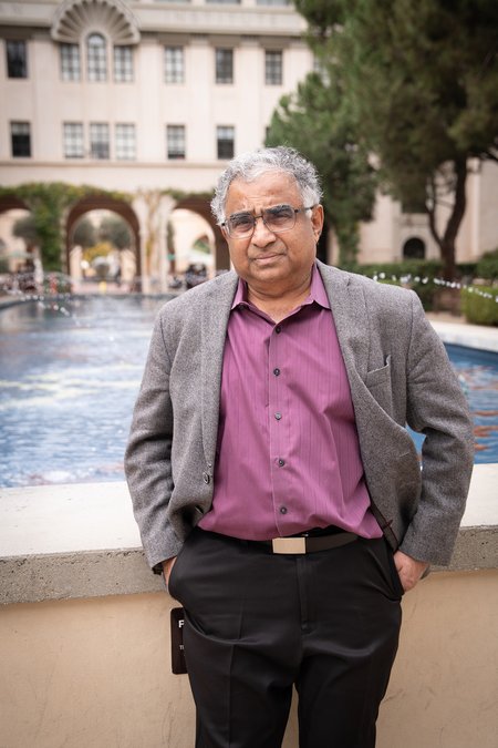 Image of Shri Kulkarni in purple shirt and grey blazer in front of fountain