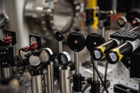 Tabletop optics in a laboratory that steer laser light as it is used to measure vibrations in a glass disk that serves as an experimental stand-in for a mirror in the Laser Interferometer Gravitational-Wave Observatory (LIGO). The experiment aims to improve LIGO mirror coatings. New coatings c twan reduce background noise in LIGO's mirrors by a factor of two, thereby increasing the volume of space that LIGO can probe by a factor of eight.