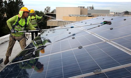 Photo of men cleaning solar panels.