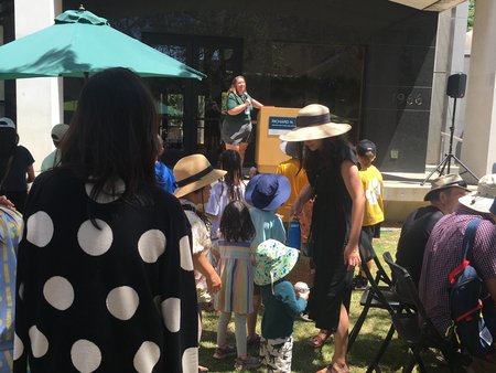 People stand watching a speaker at a podium