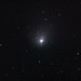 The comet appears as a glowing white blob against a background of stars