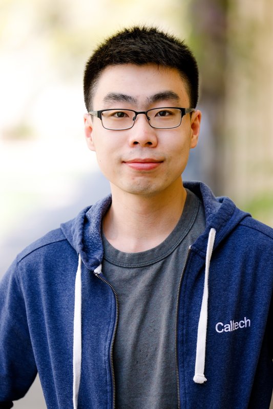 A portrait of Zhihao Cui. He wears glasses, a t-shirt and a zip-up hoodie.