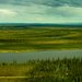 A horizontal river and green fields with a blue sky