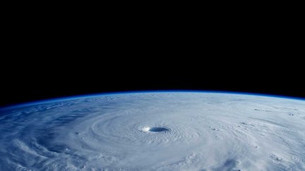 Clouds swirl in a satellite image of Earth's horizon.