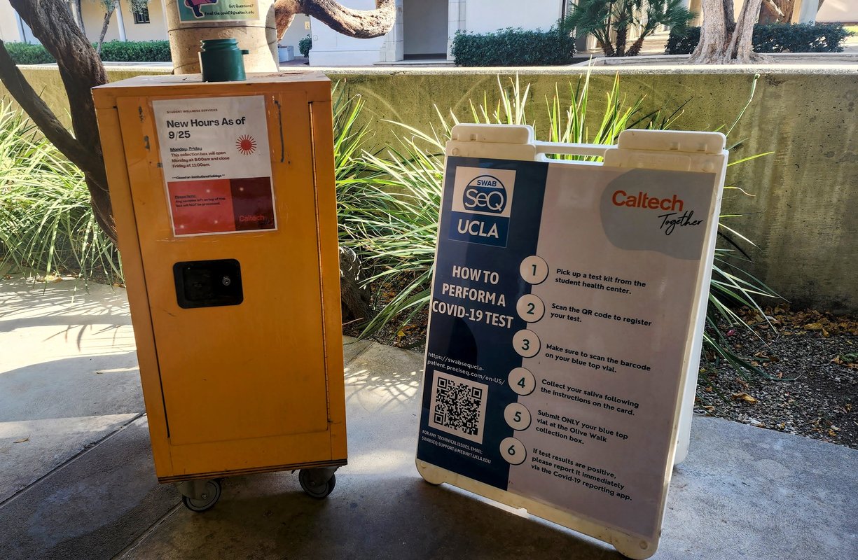 Yellow collection box next to a sign with instructions on how to perform a COVID test